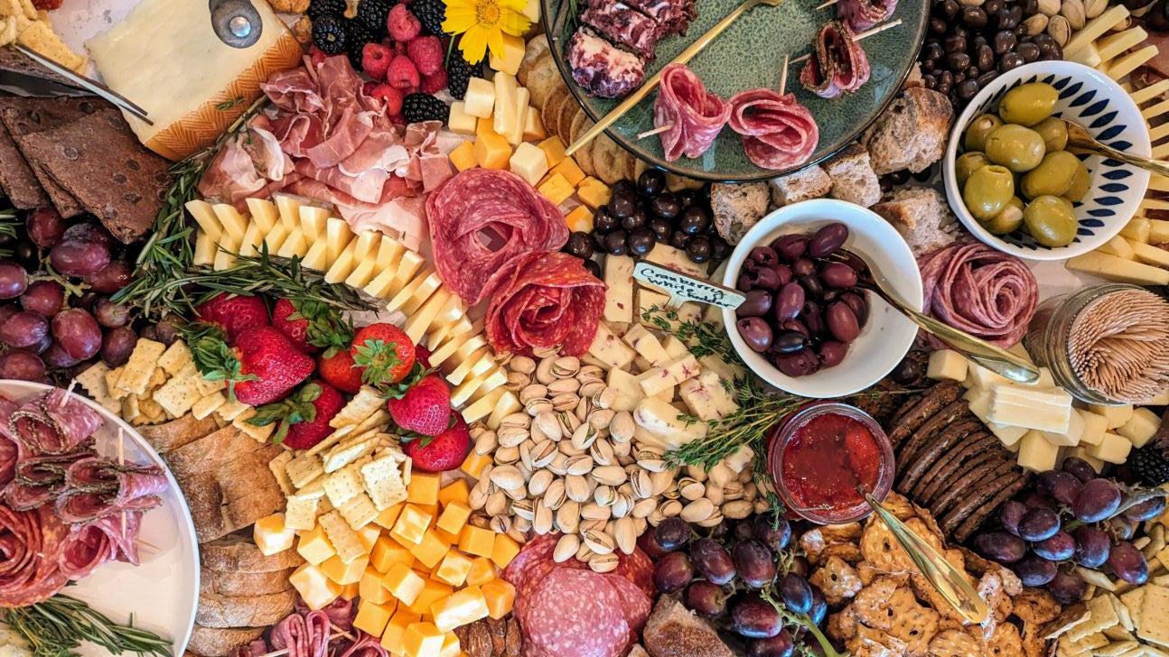 Assorted meats, cheeses, fruits, and nuts arranged on a platter.