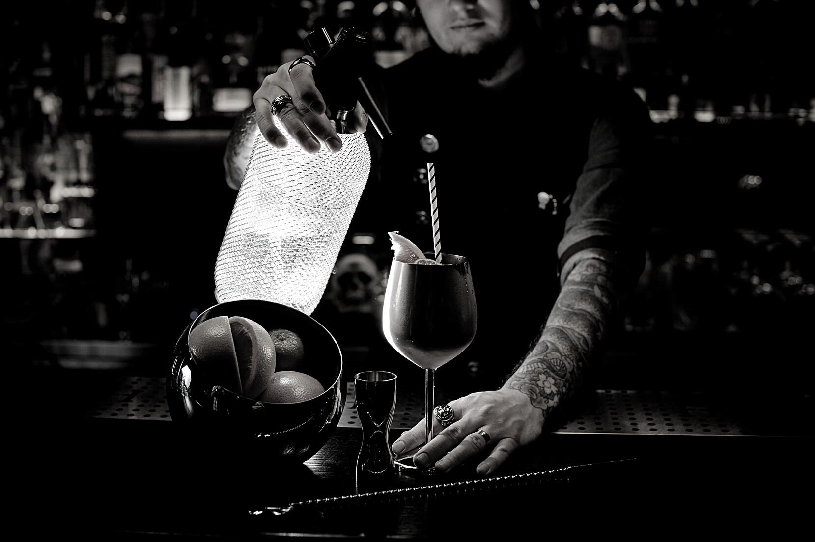 Bartender with tattoo pouring soda into the copper cocktail glass